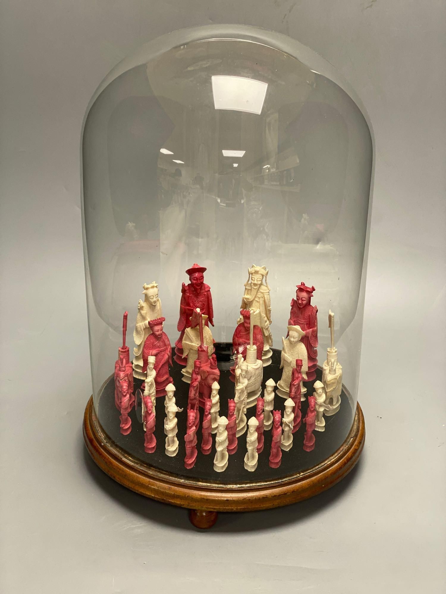 A 19th century Chinese ivory chess set, on a circular mahogany plinth, under glass dome, kings 10cm, dome 38cm